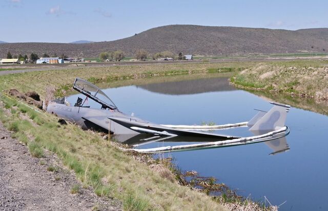 A U.S. Air Force F-15D assigned to the 173rd Fighter Wing sits in a Bureau of Reclamation canal on the south side of the runway following a mishap landing at Kingsley Field in Klamath Falls, Oregon May 15, 2023.  Absorbent booms surround the aircraft as precaution against the leakage of fuel or other substances.  (U.S. Air National Guard photo by Master Sgt. Jefferson Thompson)  